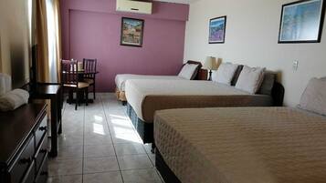 Una habitación de hotel con dos camas, un escritorio, una silla y un ventanal con cortinas.