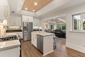 A modern kitchen with white cabinetry, stainless steel appliances, and a central island. - The Southern Whippoorwill on East Beach with Pool, sleeps 10 (St Simons Island)