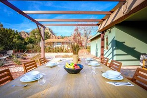 A wooden dining table set for six with a bowl of fruit in the center, surrounded by chairs.