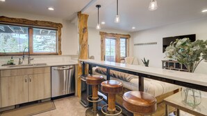 Una cocina moderna con armarios de madera, electrodomésticos de acero inoxidable y una barra con taburetes.