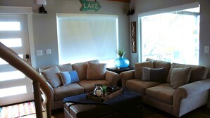 Una sala de estar con dos sofás, una mesa de centro y un ventanal con vistas a un lago.