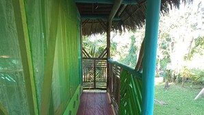 A covered wooden walkway with green walls and a thatched roof.