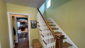 A wooden staircase with white railings leading to a second-floor landing. A sign on the wall reads "Onionagons Michigan." - Your adventure home base for skiing, snowboarding, hiking and biking! (Ironwood)