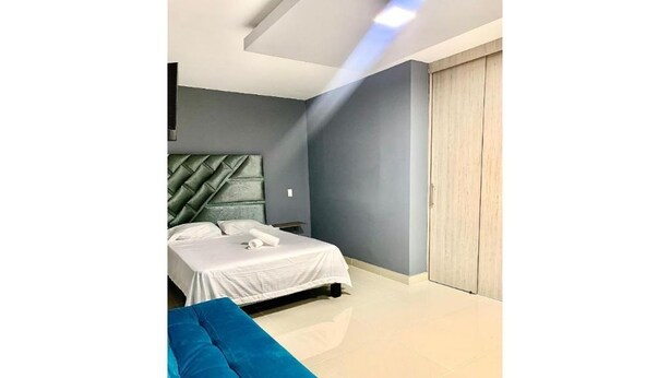 Een moderne slaapkamer met een bed, een blauwe bank en een kledingkast.