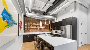 Una cocina moderna con una isla grande, taburetes de bar, electrodomésticos de acero inoxidable y un salpicadero de ladrillo.