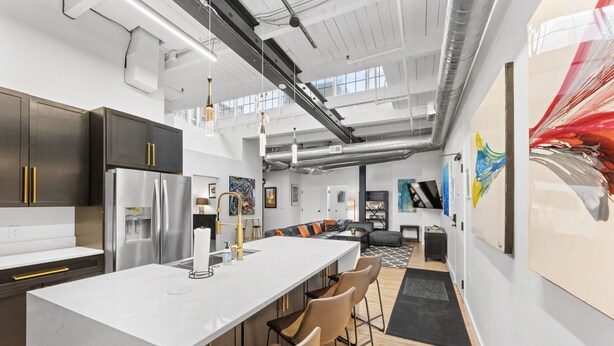 Una cocina moderna con una isla central, electrodomésticos de acero inoxidable y una zona de bar con taburetes.