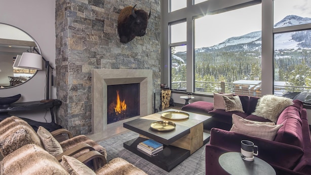 Un salon chaleureux avec une cheminée en pierre, des meubles confortables et une vue sur les montagnes.