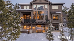 Une maison moderne à deux étages, dotée d’un balcon, de grandes fenêtres et offrant une vue sur la montagne.