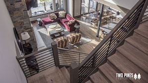 Un vaste espace de vie agrémenté d’un canapé rouge, d’un parquet en bois et d’un escalier doté d’une rampe en métal.