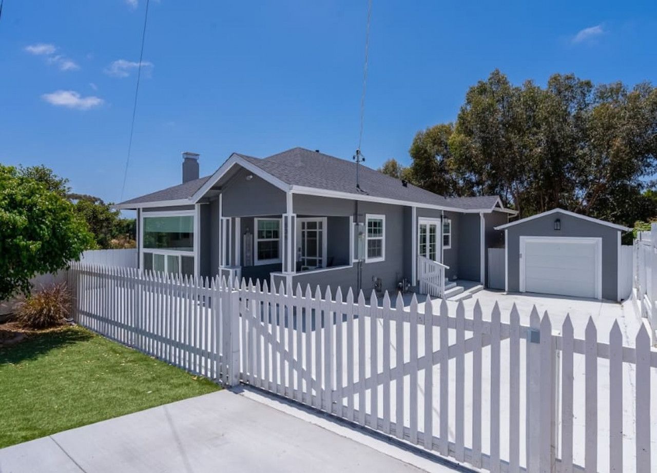 A residential house with a white picket fence, a garage, and a well-maintained lawn.