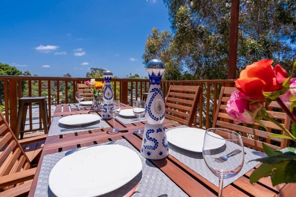 An outdoor dining area with wooden tables and chairs, white plates, and blue and white decorative vases.