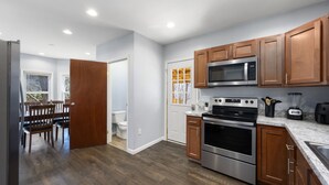 Une cuisine moderne avec des meubles en bois, des appareils en acier inoxydable et un coin repas comprenant une table et des chaises.