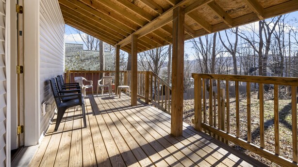 Une terrasse en bois dotée d’une rambarde, de bancs et offrant une vue sur une zone boisée.