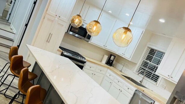 Una cocina moderna con una isla de mármol, electrodomésticos de acero inoxidable e iluminación colgante.