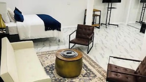 Una habitación de hotel moderna con cama, sofá, mesa de centro y televisor.