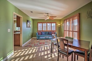 Relax in this spacious room with a high ceiling, ceiling fan, and large window with wooden blinds.