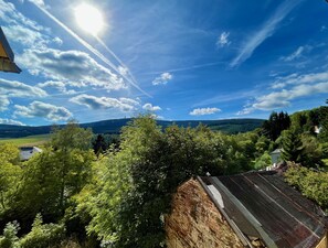 A view of a rural landscape with a hill, trees, and a building with a sloped roof. - Landhaus-Chalet-Keilberger Blick  (Oberwiesenthal)