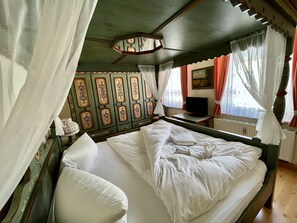 A room with a bed, a television on a small table, and a window with curtains. - Landhaus-Chalet-Keilberger Blick  (Oberwiesenthal)