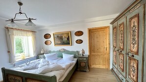 Un dormitorio tradicional con cama, mesitas de noche, armario y ventana con cortinas.