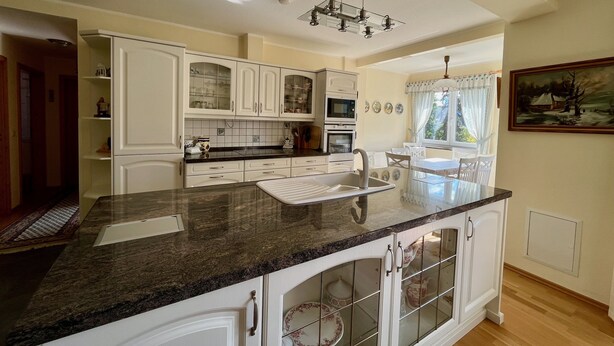 Una cocina moderna con muebles blancos, encimera de granito y horno empotrado.