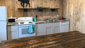 A kitchen with wooden walls, a white stove, a microwave, and a sink.