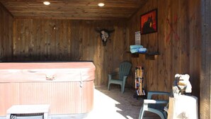 A rustic wooden room with a hot tub, a chair, and a wooden sculpture. - 2 Queen Beds, Full Bathroom, Shared Hot Tub, WIFI (Island Park)