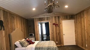 A bedroom with a bed, a dresser, a mirror, and a door leading to a bathroom. - Full Bathroom, 2 Queen Beds, WIFI, Shared Hot Tub (Island Park)
