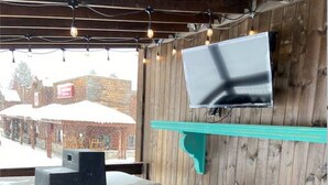 A hot tub under a wooden roof with a television mounted on the wall. - Hot Tub, Full Kitchen, Gas Fireplace, BBQ Grill (Island Park)