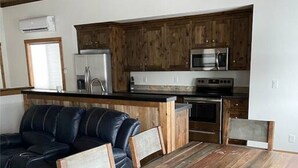A modern kitchen with wooden cabinets, stainless steel appliances, and a built-in oven. - Hot Tub, Full Kitchen, Gas Fireplace, BBQ Grill (Island Park)