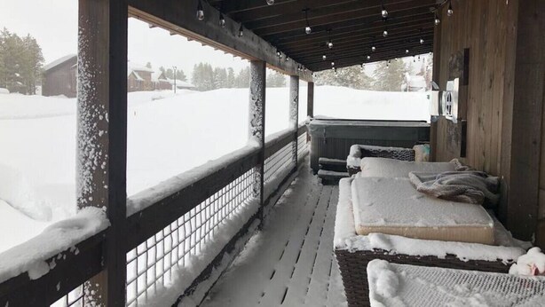 A covered outdoor seating area with benches and a view of a snowy landscape. - Hot Tub, Full Kitchen, Gas Fireplace, BBQ Grill (Island Park)