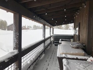 A covered outdoor seating area with benches and a view of a snowy landscape. - Hot Tub, Full Kitchen, Gas Fireplace, BBQ Grill (Island Park)