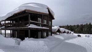 A wooden cabin with a covered porch, surrounded by snow. - Hot Tub, Full Kitchen, Gas Fireplace, BBQ Grill (Island Park)