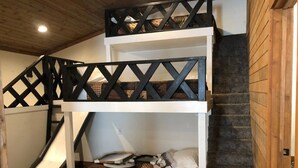Un lit superposé avec une échelle, un petit bureau et un toboggan.
