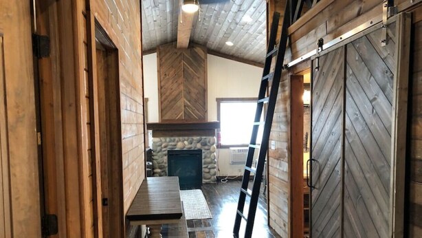 Un intérieur en bois avec une cheminée en pierre, un coin repas et une porte coulissante de style grange.