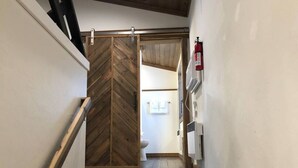 Un couloir étroit avec une porte en bois donnant sur une salle de bain.