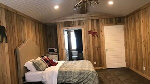 A bedroom with a bed, a dresser, and a door leading to a bathroom. - Shared Hot Tub, WIFI, 2 Queen Beds, Full Bathroom (Island Park)