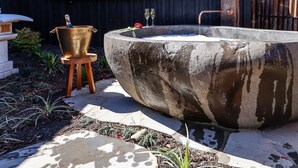 Ein großes Außenwhirlpool mit einem Holzschemel und einer Rose daneben.