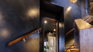 A modern staircase with wooden steps and metal railings, leading to a room with a dark wall and a visible door. - Unique luxury + salvage + African theming = Heaven (Hepburn Springs)