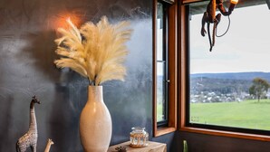 A wooden console table with a vase of pampas grass, a giraffe figurine, and a small decorative item. - Unique luxury + salvage + African theming = Heaven (Hepburn Springs)