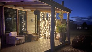 A covered outdoor seating area with wicker furniture and string lights.