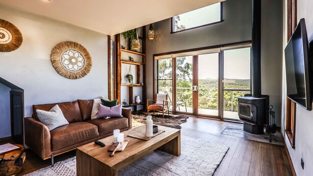Una sala de estar moderna con un sofá de cuero, una mesa de centro de madera y un ventanal con vistas al exterior.