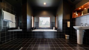 Un baño moderno con una bañera grande, dos lavabos y un ventanal que proporciona luz natural.