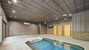 Una piscina interior amb terra de formigó, zona d'estar integrada i portes de fusta.