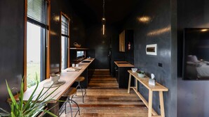 Una cucina moderna con un lungo bancone in legno, pareti nere e un lampadario.