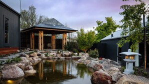 Ein Teich mit Steinen und einem hölzernen Pavillon.
