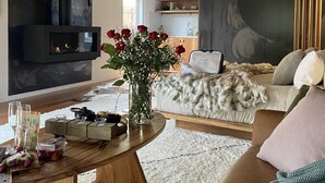 A modern living room with a fireplace, a round wooden coffee table, and a sofa with a fur throw.