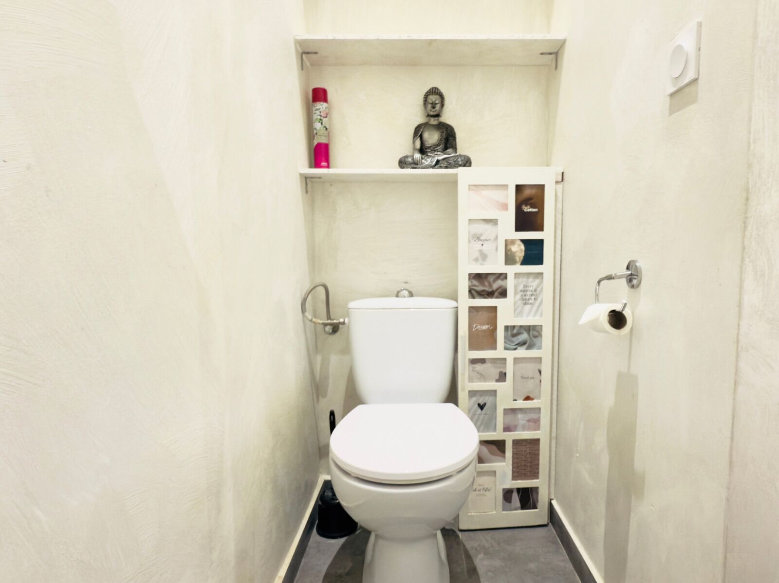 A small, white bathroom with a toilet, a shelf with a statue, and a wall-mounted toilet paper holder.