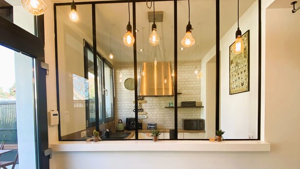 A modern kitchen with a large mirror above the counter, pendant lights, and a view of the outdoor patio. - Cosy duplex - between lakes and mountains - NO PARTIES ALLOWED (Fillinges)