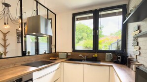 A modern kitchen with a large window, a built-in oven, and a coffee machine. - Cosy duplex - between lakes and mountains - NO PARTIES ALLOWED (Fillinges)