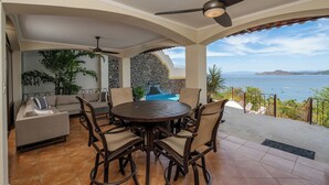 An outdoor patio with a round table and chairs, a sofa, and a ceiling fan. - Mariners Point C1 – 3-Bedroom Villa on Bluff Above Playa Hermosa with Private Pool (Playa Hermosa)